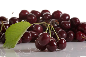 Cherry twig with ripe fresh cherries. In the background is a group of cherries.