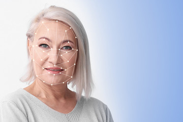 Facial recognition system. Mature woman with biometric identification scanning grid on light...
