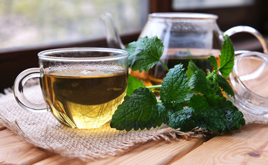 Fragrant fresh herbal tea made from mint, Melissa and Ivan tea in a glass Cup and teapot on a dark wooden background. Traditional herbal drink. Space for text or design.