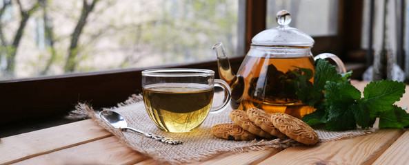 Fragrant fresh herbal tea made from mint, Melissa and Ivan tea in a glass Cup and teapot on a dark wooden background. Traditional herbal drink. Space for text or design.