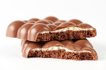 Composition of bars and pieces of porous milk chocolate with a coconut layer closeup on a white background isolated