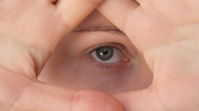 A young woman shows a symbol of the Illuminati, an eye in a triangle. Pyramid of Masons and Illuminati - Powered by Adobe
