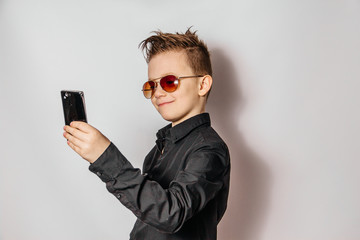 a fashionable guy in sunglasses and a black shirt with a cool hairstyle looks at the phone and...