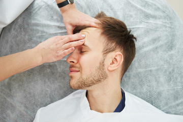 Obraz na płótnie Canvas Handsome caucasian man has facial massage in cosmetologist's office close-up. Men's beauty procedures, beautician face skin care
