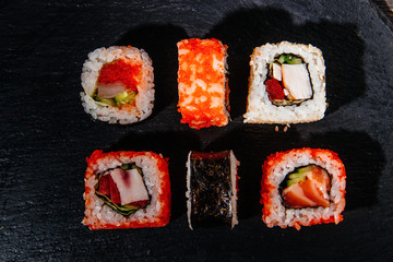 Beautiful and delicious variety of sushi rolls laid out on a stone board. - 344612939