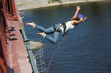Fototapeta na wymiar Rope jumping. Girl in helmet starting to jump from a bridge