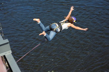 Fototapeta na wymiar Rope jumping. Girl in helmet starting to jump from a bridge
