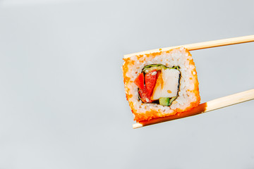 One sushi roll held by chopsticks on a white background - 344613524