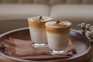 Two glasses of Dalgona iced coffee on a wooden tray. Trendy whipped coffee.