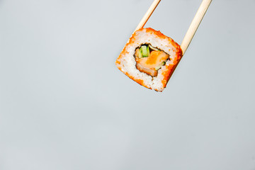 One sushi roll held by chopsticks on a white background - 344613791