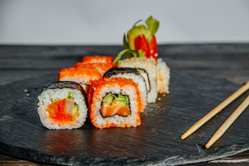 Beautiful and delicious variety of sushi rolls laid out on a stone board. - 344614168