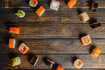 Sushi rolls laid out on a wooden dark table, in the center of copyspace - 344614767
