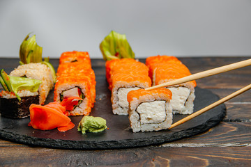 Beautiful and delicious variety of sushi rolls laid out on a stone board. - 344614996