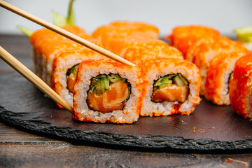 Beautiful and delicious variety of sushi rolls laid out on a stone board.