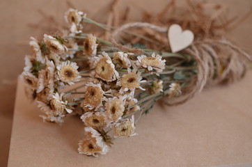 dry flowers in craft paper with ribbon and heart