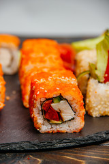 Beautiful and delicious variety of sushi rolls laid out on a stone board. - 344615183