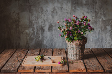 Beautiful bouquets of wildflowers on a wooden table on a cold concrete wall background.