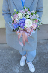 Flower arrangement in a pink hat box was created by a florist for a wedding gift. Flower bouquet of blue hydrangea, white Freesia, pink Ranunculus asiaticus, eustoma flowers, roses and eucalyptus