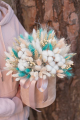 Composition of  cozy flowers in 
beige hat box. Floral bouquet of flowers of cotton flowers, gypsophila, wheat and lagurus for a gift for home decor