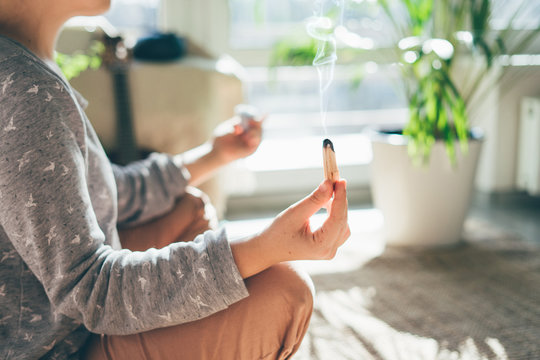 Young beautiful woman is meditating with palo santo in hand.