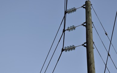 Power line with glass insulators and wires. One power pole off center, room for copy.  Blue sky in...