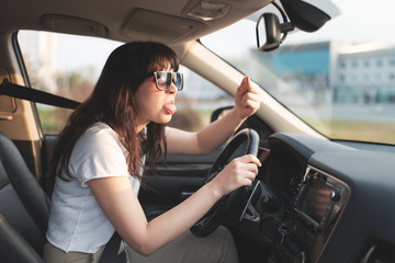 Road conflict. Woman showing middle finger and jeering someone outside her car. - obrazy, fototapety, plakaty