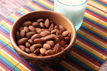 close up of almond nut in a bowl and milk on table.