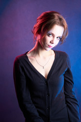 Beautiful girl model in a black blouse. Studio portrait on a blue background red light circuit.
