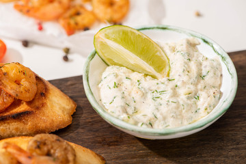 close up view of canape with fried shrimps with sauce, lime on wooden board