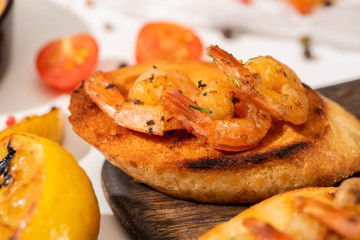close up view of canape with toast bread and fried shrimps on wooden board
