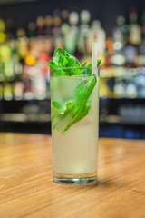 Cocktail prepared, on wooden table and bar background, with bottles and lights.