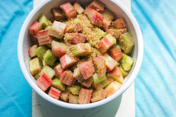 Bowl with cut rhubarb and golden sugar