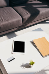 living room with grey sofa and table with digital tablet, notepad, credit card and succulent