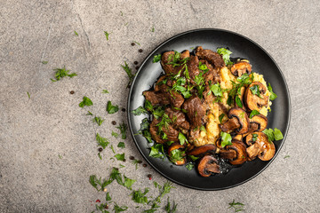 Stewed beef with mushrooms and a side dish of lentils on a black plate. Top view with place for text.