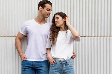Young couple standing together leaning on urban wall