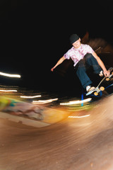 A young skater at night in a skatepark does the trick on the railing. X-ray culture nightlife concept © yanik88