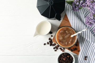 Composition with ice coffee and flowers on white wooden background