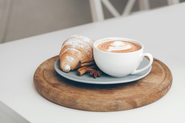 Fresh baked croissant with coffee cup and latte art, cinnamon