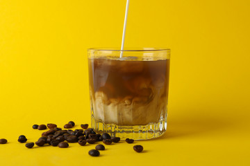 Glass of ice coffee on yellow background. Fresh drink