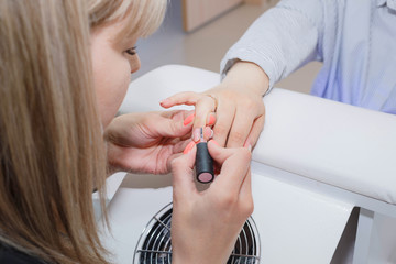 Manicuring nails - application of base coat. Selective focus, high key