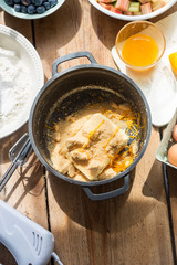 Preparing fruit (rhubarb, blueberry) orange cake. Butter with golden sugar and orange peel, flour, eggs, orange juice 
