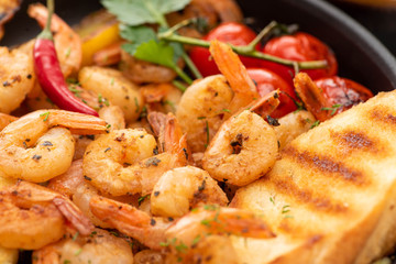 close up view of fried shrimps with grilled bread, tomatoes, chili peppers