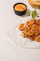 fried shrimps on parchment paper with sauce and lime on white background