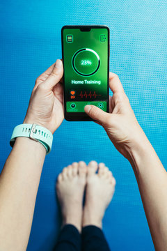 woman using smartphone during workout at home. Young sporty woman holding a smartphone.
