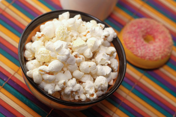 salted popcorn in a bowl and donut on table 