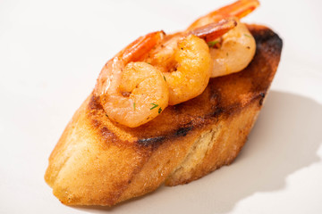 close up view of canape with toast bread and fried shrimps on white background
