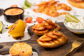 selective focus of canape with fried shrimps with sauce on wooden board