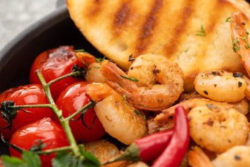 close up view of fried shrimps with grilled bread, tomatoes, chili peppers
