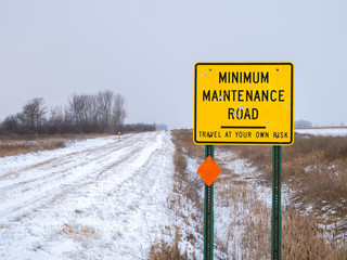 Yellow Road Sign warning of MINIMUM MAINTENANCE ROAD In rural Minnesota on an overcast early winter...