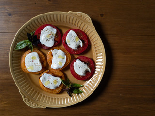 Sliced red and orange tomatoes with mozzarella, olive oil, basil